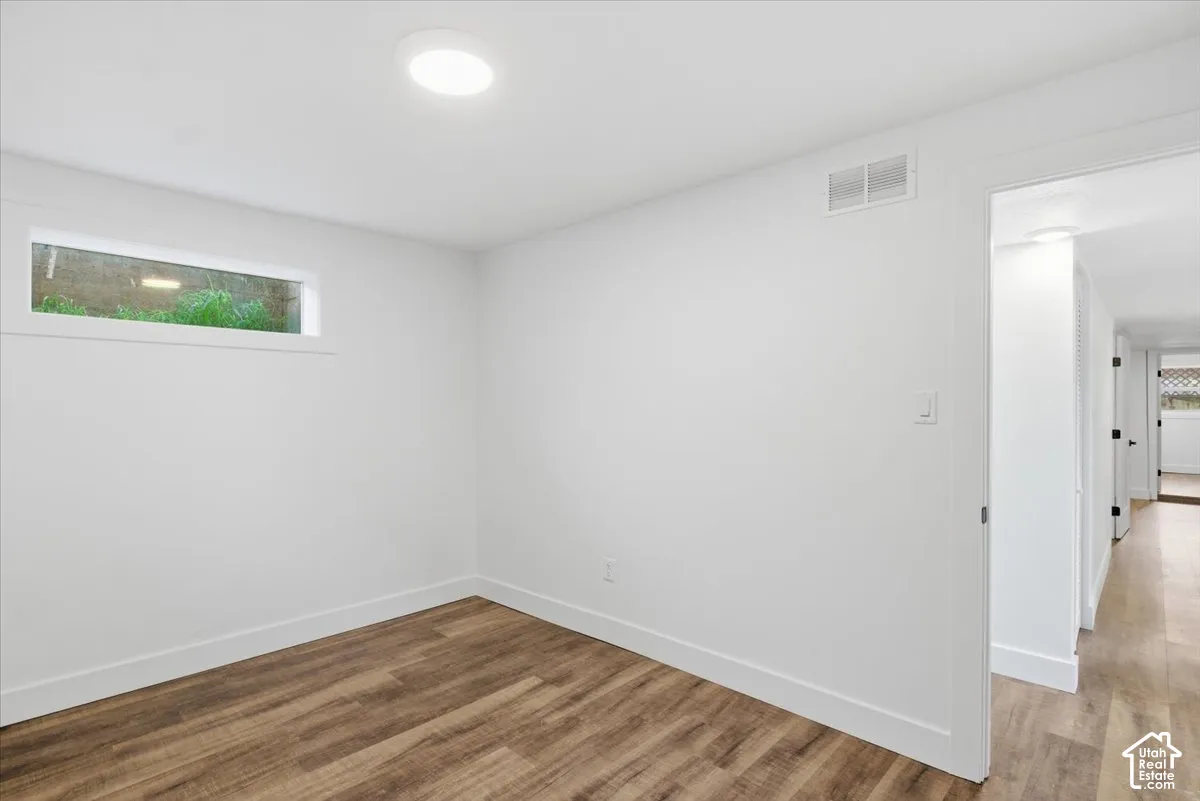 Wood-finish flooring, white walls, flush-mount ceiling light, and a horizontal window