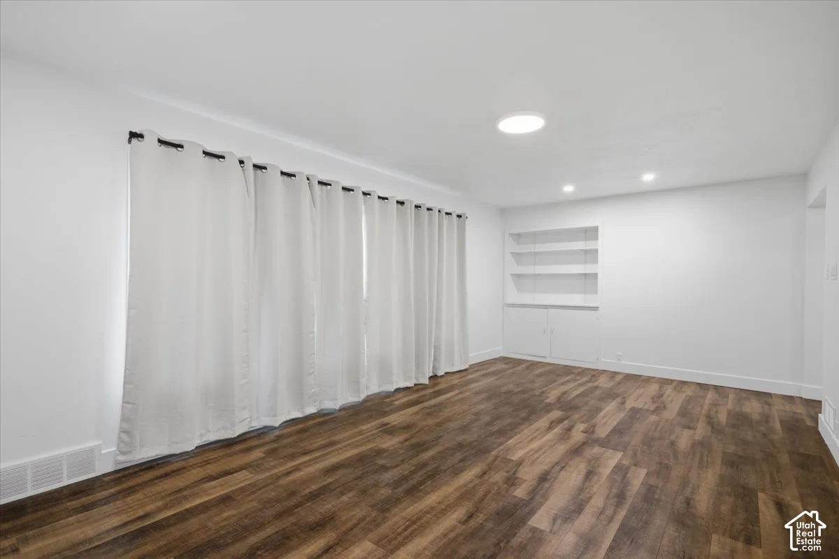 Wood-finish flooring, recessed lighting, built-in shelving, and white walls