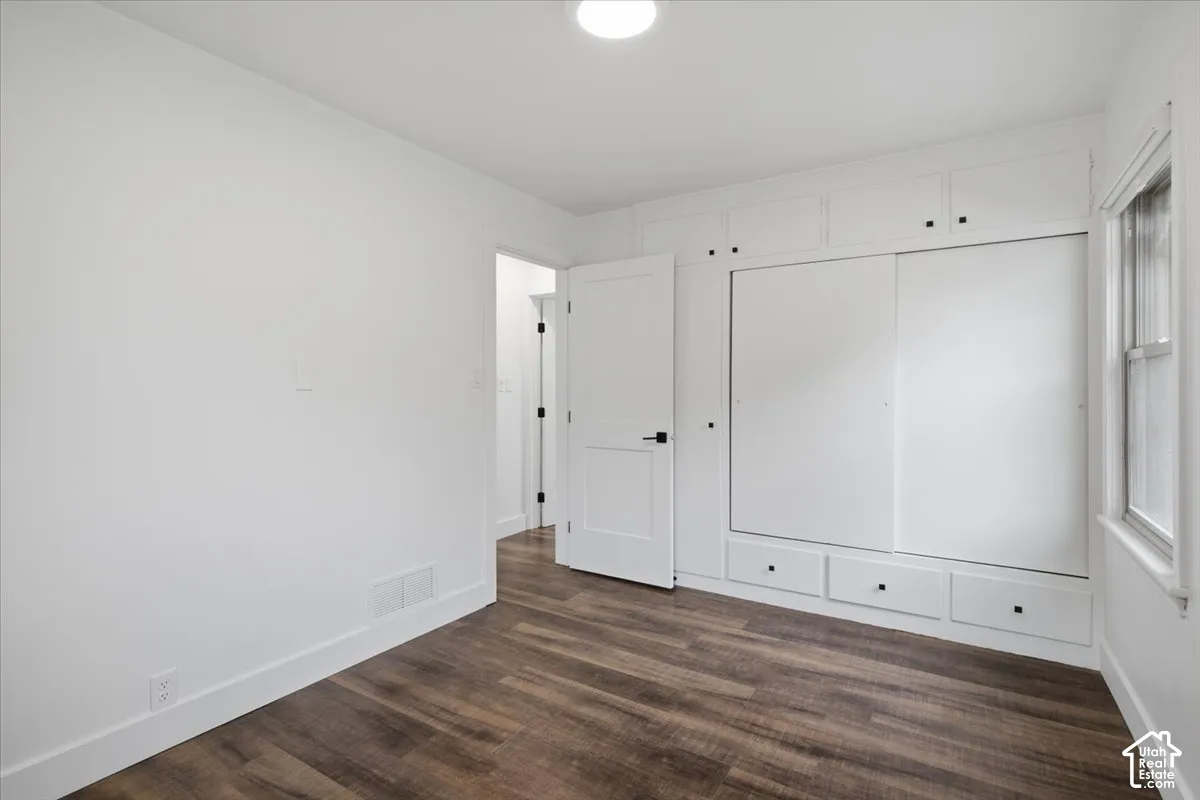 Built-in white cabinetry with sliding doors and drawer storage, wood-finish flooring, white trim, and a window