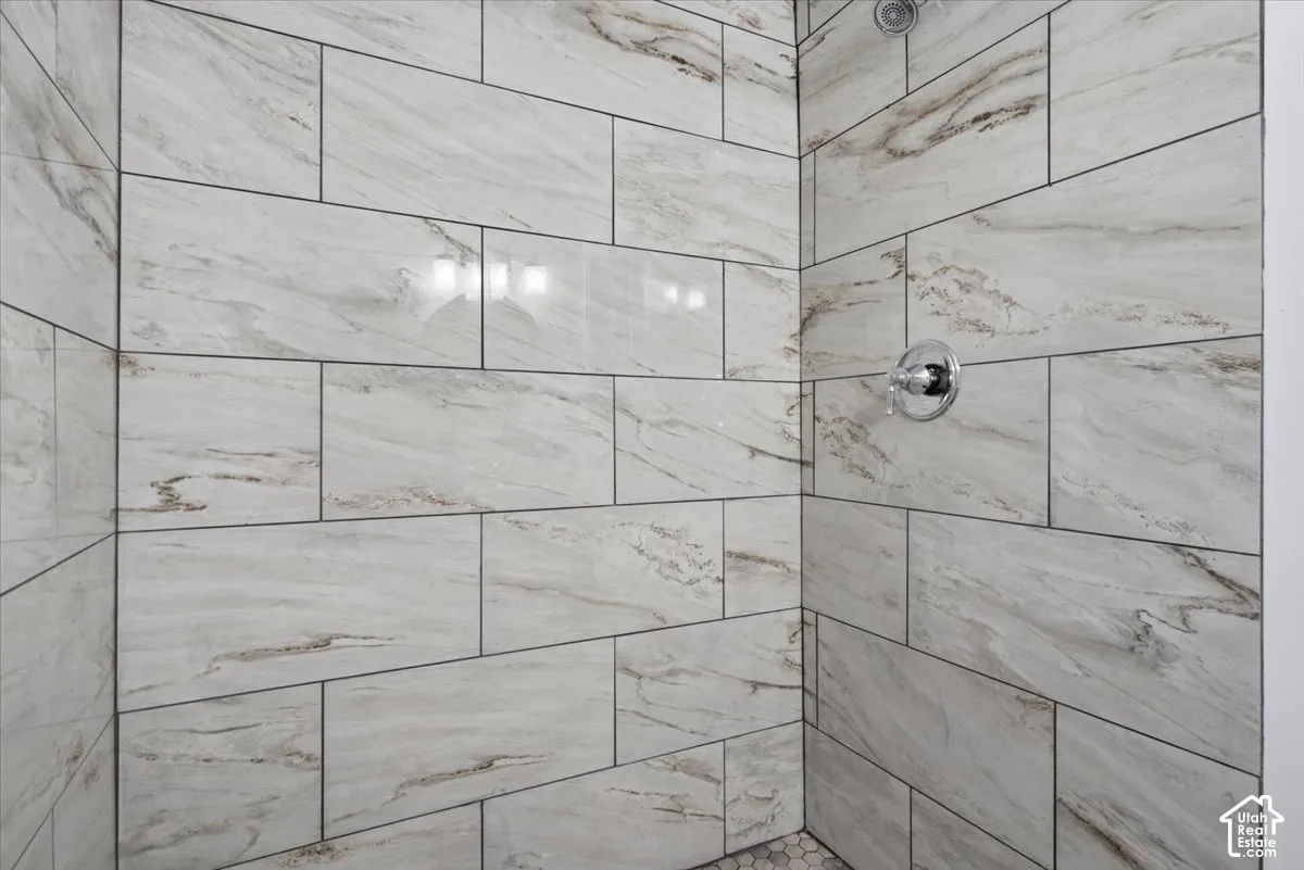 Spa-inspired shower enclosure featuring large-format porcelain tile with natural wood-grain finish, seamless glass enclosure, and polished chrome showerhead and fixtures
