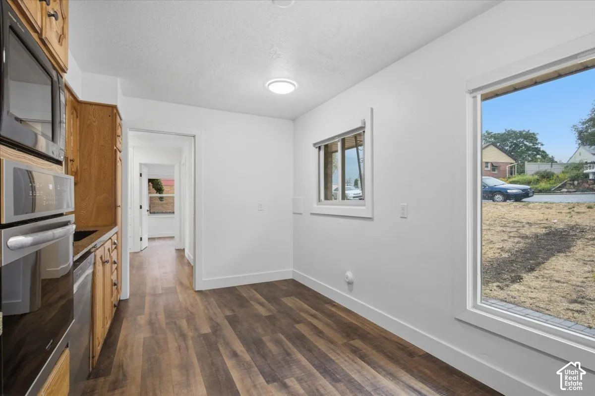 Wood-finish flooring, built-in stainless steel appliances, wood cabinetry, recessed lighting, and a large window