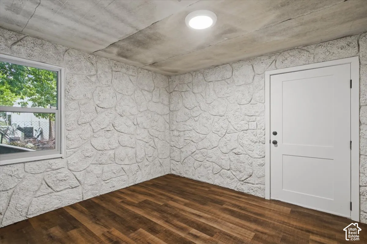Textured stone-look wall finish, wood-finish flooring, white panel door, and white frame window