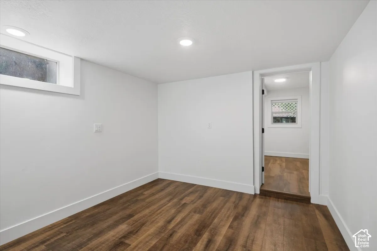 Wood-finish flooring throughout, recessed ceiling lighting, crisp white walls, and a window with white trim