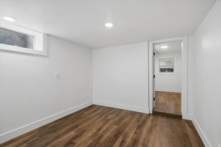 Wood-finish flooring throughout, recessed ceiling lighting, crisp white walls, and a window with white trim