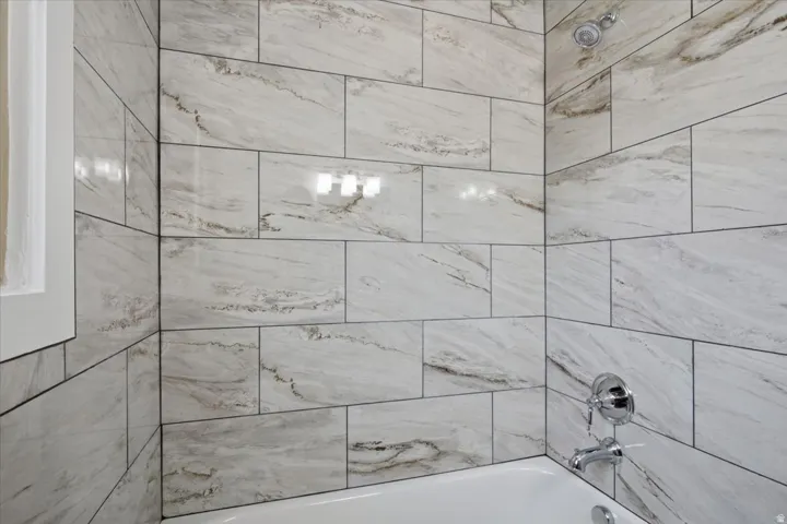 White subway tile shower surround with contrasting dark grout, chrome showerhead, and tub filler