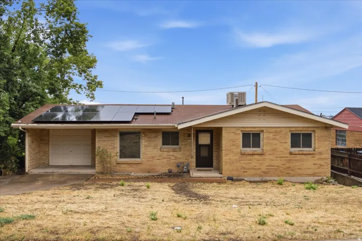 Brick exterior featuring solar panels, an attached garage, and a covered entry