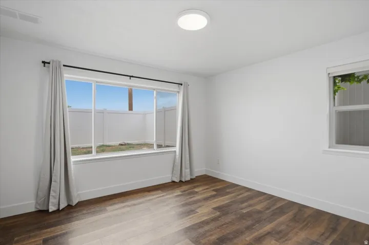 Wood-finish flooring, white walls, two windows, and a flush-mount ceiling light
