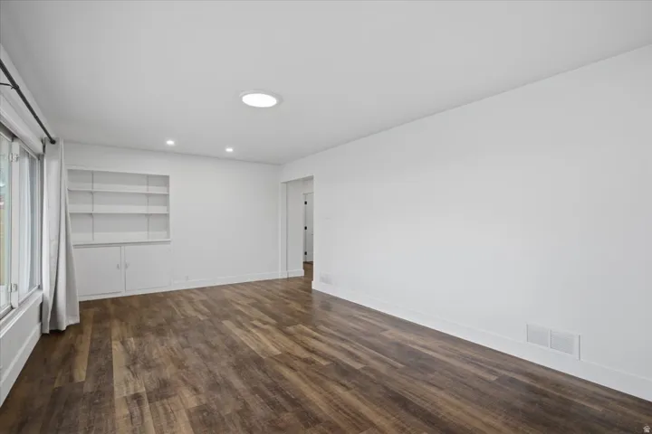 Wood-finish flooring, recessed lighting, built-in shelving, and large windows