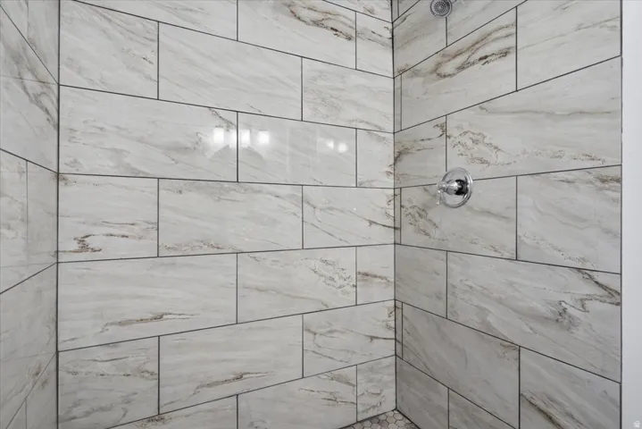 Spa-inspired shower enclosure featuring large-format porcelain tile with natural wood-grain finish, seamless glass enclosure, and polished chrome showerhead and fixtures