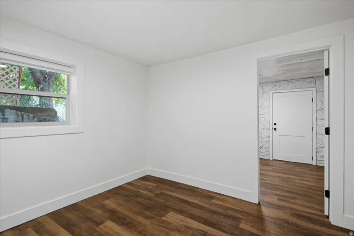 Wood-finish flooring, white walls, and a white window frame with a lattice pattern