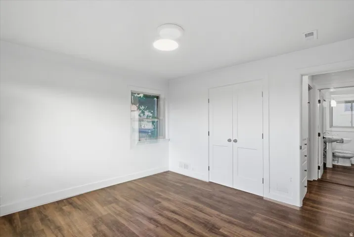 Wood-finish flooring throughout, bright white walls, built-in closet with double doors, and a ceiling-mounted light fixture