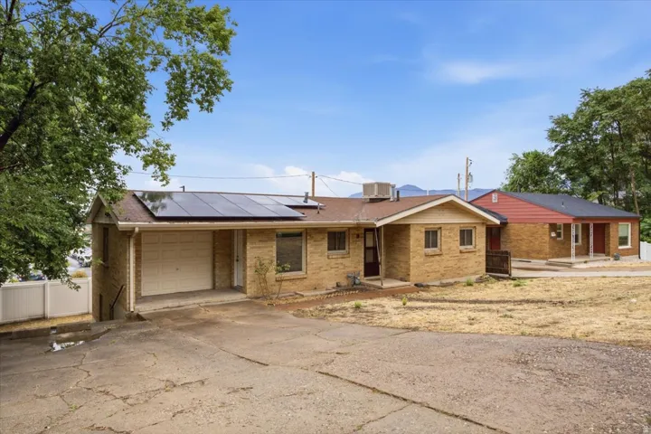 Brick exterior with integrated solar panels, attached garage, and paved driveway