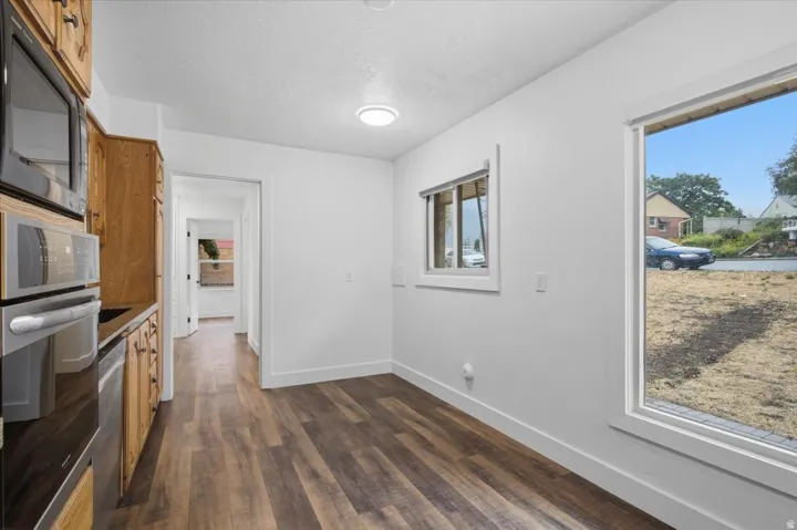 Wood-finish flooring, built-in stainless steel appliances, wood cabinetry, recessed lighting, and a large window
