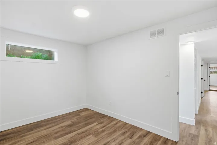 Wood-finish flooring, white walls, flush-mount ceiling light, and a horizontal window