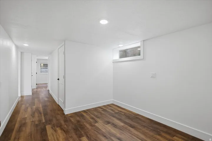 Recessed lighting, wood-finish flooring, white paneled doors, and a window well provide illumination