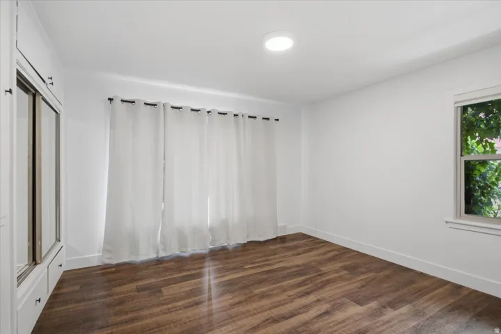 Recessed ceiling light, wood-finish flooring, built-in cabinetry with mirrored doors, window with exterior foliage