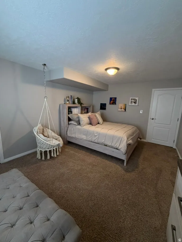 Spacious bedroom featuring a gray accent wall, built-in shelving with display space, recessed ceiling lighting, and carpeted flooring