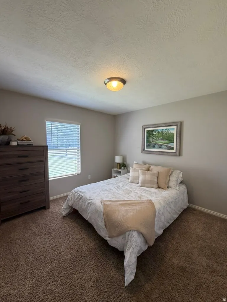Bright secondary bedroom featuring neutral wall finishes, carpeted flooring, recessed ceiling lighting, and a large window with blinds providing natural light