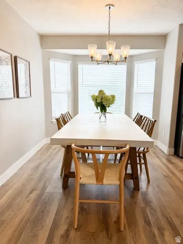 Bay window with multiple panels, wood-finish flooring, and a five-light chandelier with frosted glass shades