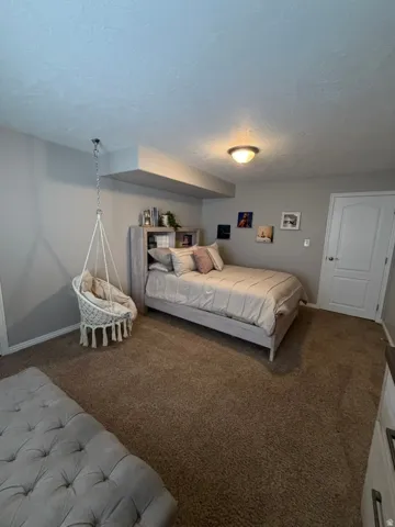 Spacious bedroom featuring a gray accent wall, built-in shelving with display space, recessed ceiling lighting, and carpeted flooring