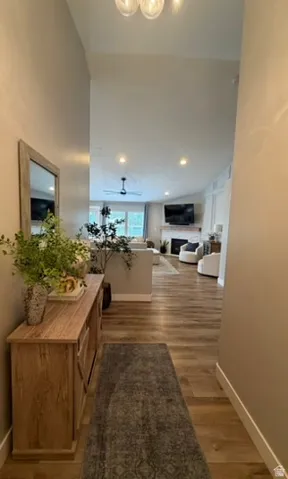 Vaulted ceiling with an attached light fixture, wood-finish flooring, recessed lighting, and a ceiling fan