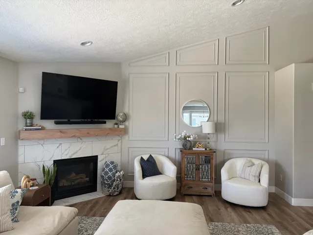 Vaulted ceiling, recessed lighting, fireplace with a wood mantel and marble-look tile surround, wood-finish flooring, and decorative wall paneling