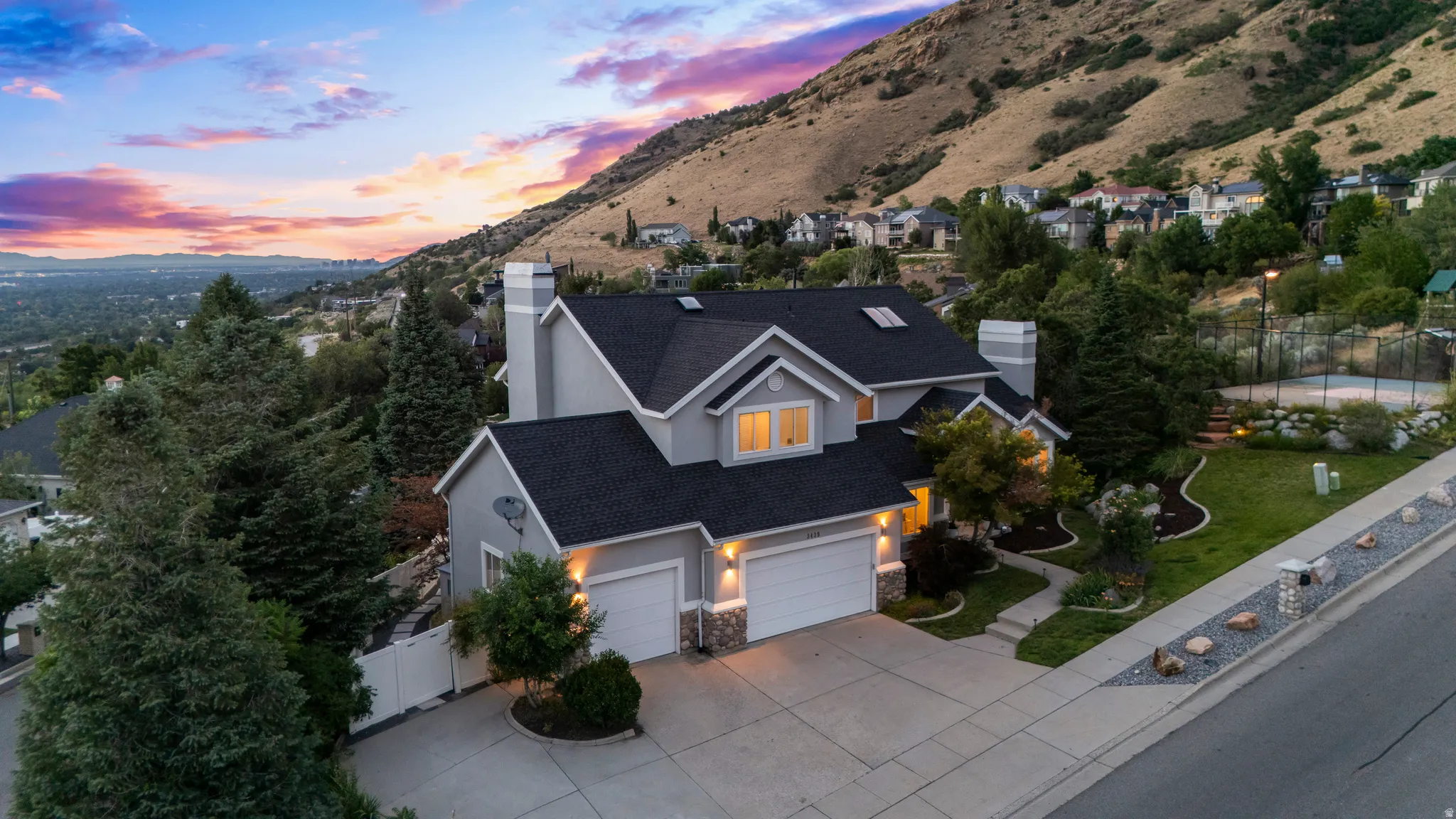 Two-story residence with a multi-car garage, stone accents, and a dark shingle roof