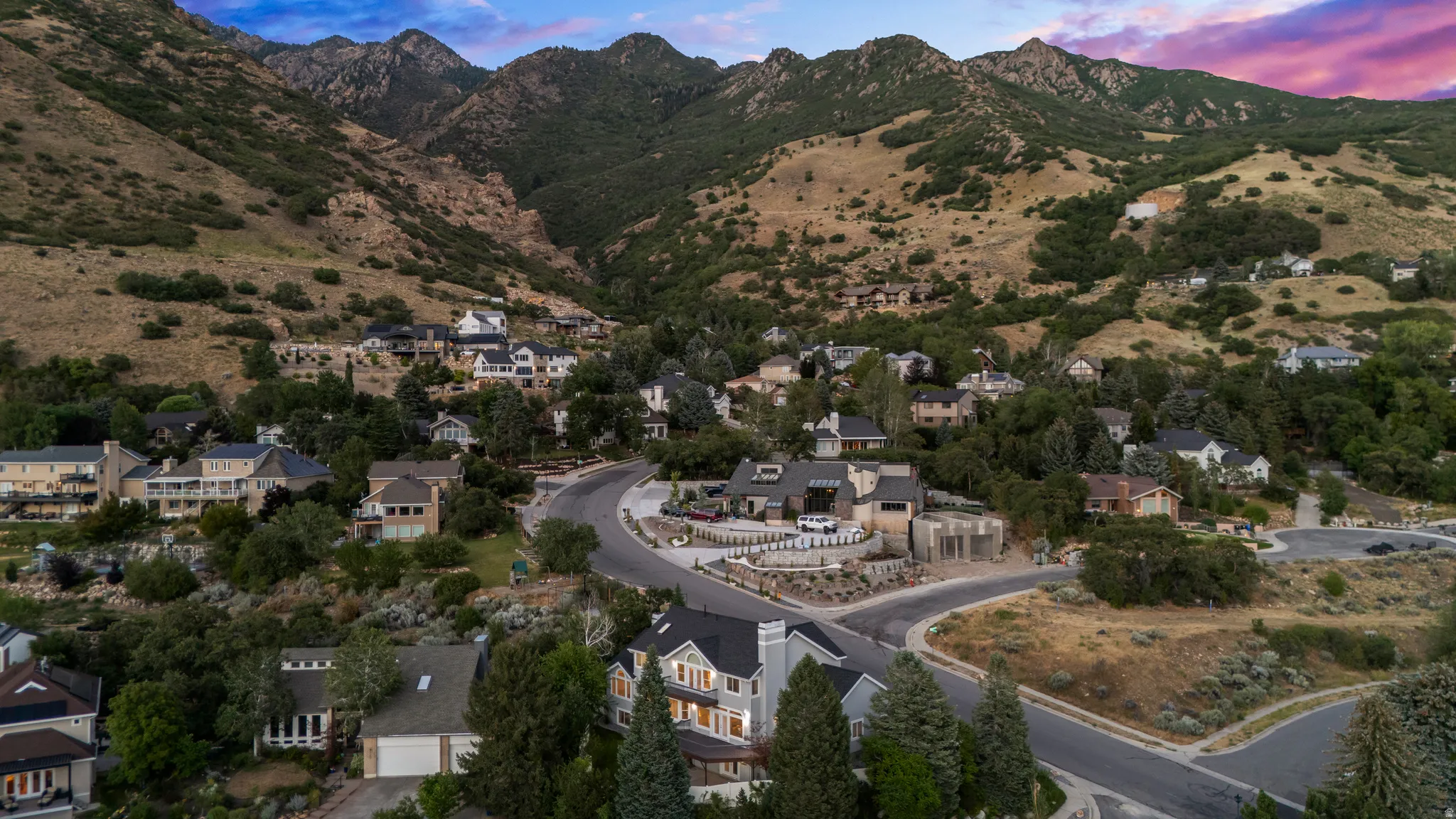 Mountainous terrain, residential properties, winding roads, and abundant natural landscaping