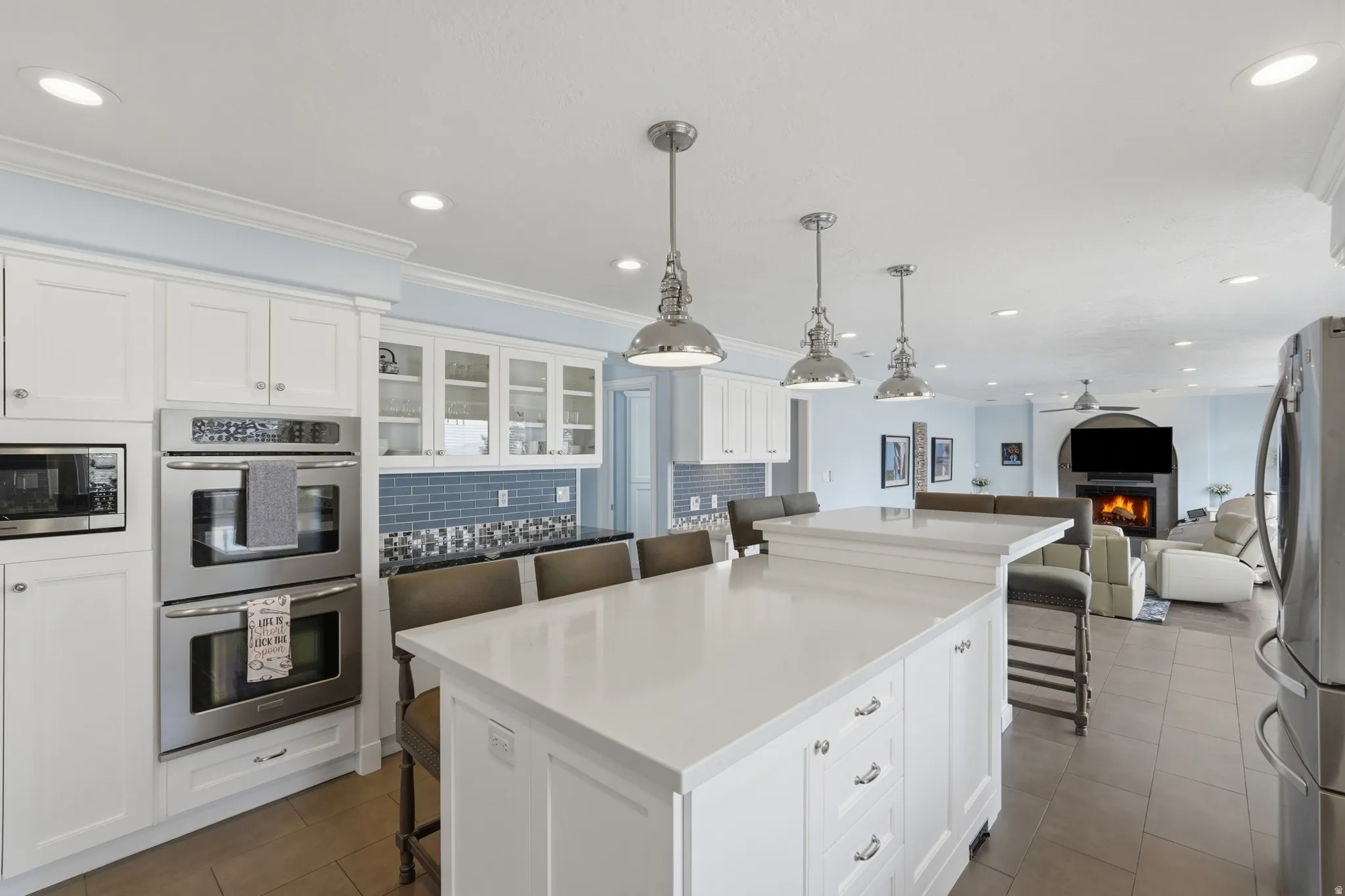 Kitchen featuring white cabinetry, a large kitchen island with counter seating, stainless steel double wall ovens, a tile backsplash, and recessed lighting