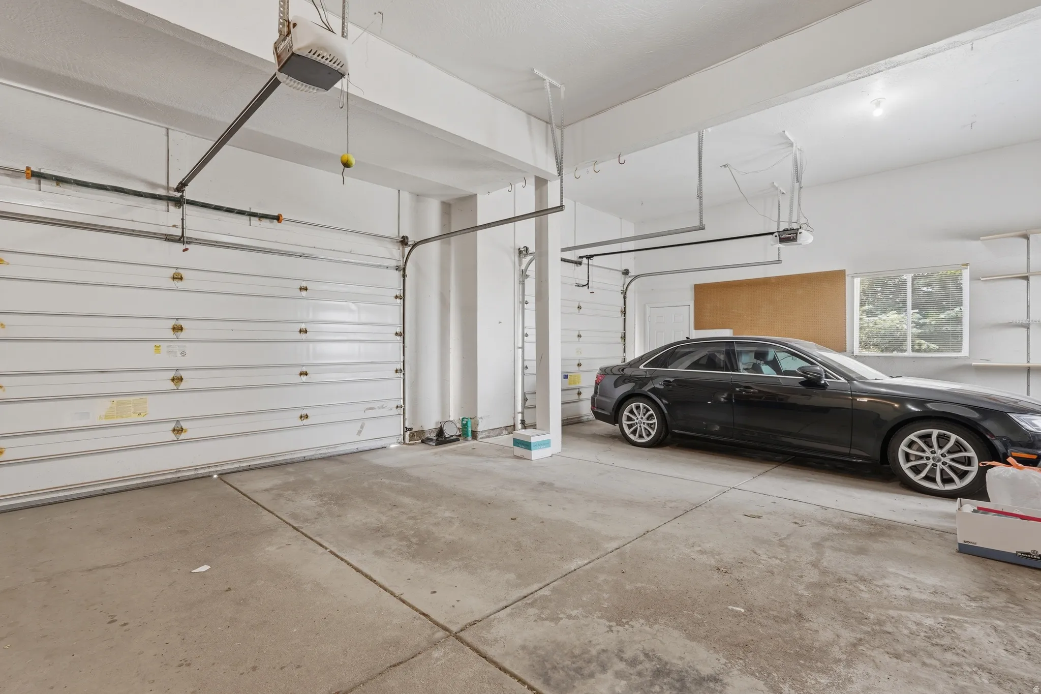 Spacious garage with multiple overhead doors, concrete flooring, and built-in shelving