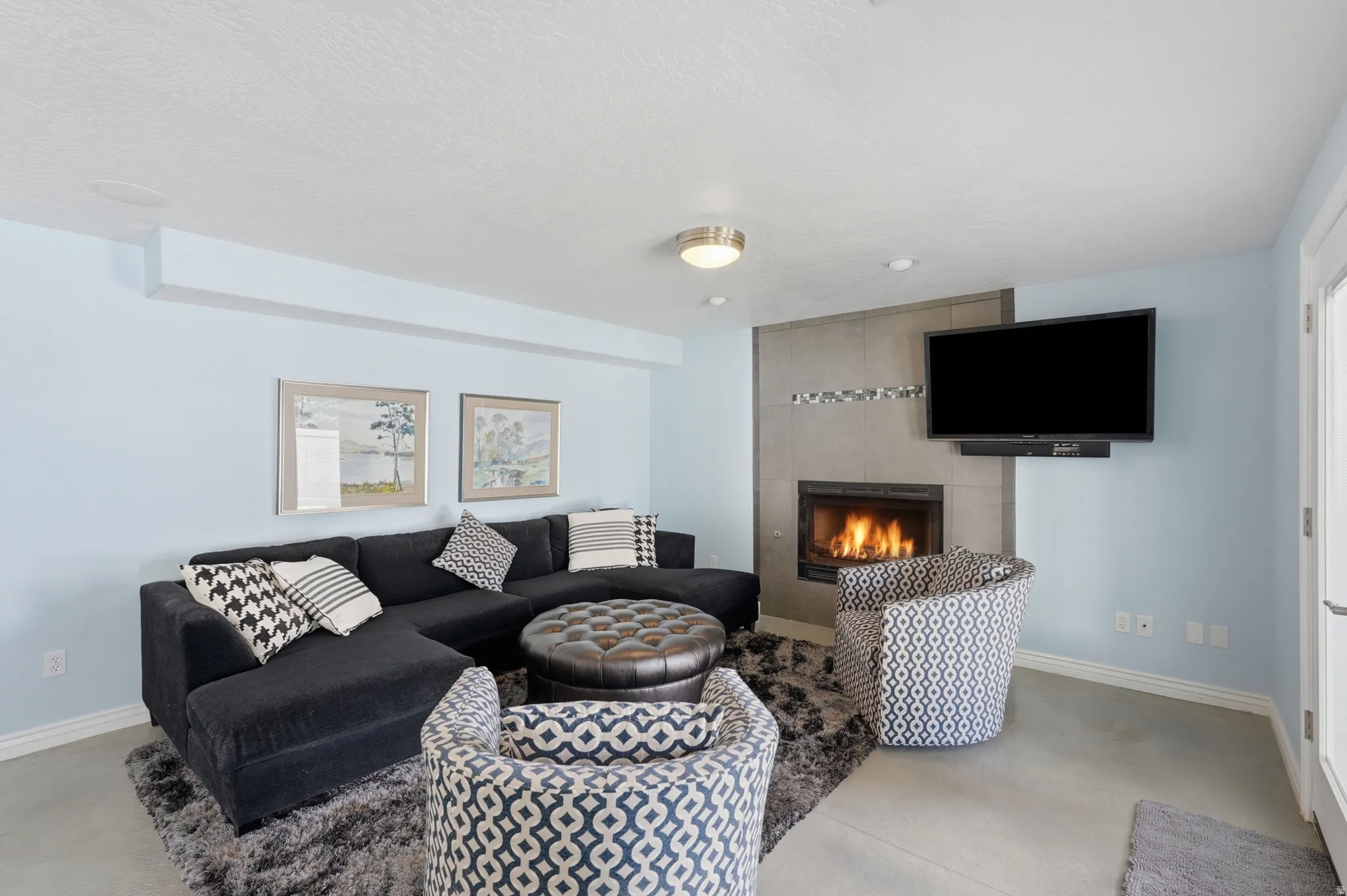 Tile-faced fireplace with a built-in firebox, wall-mounted television, and recessed lighting