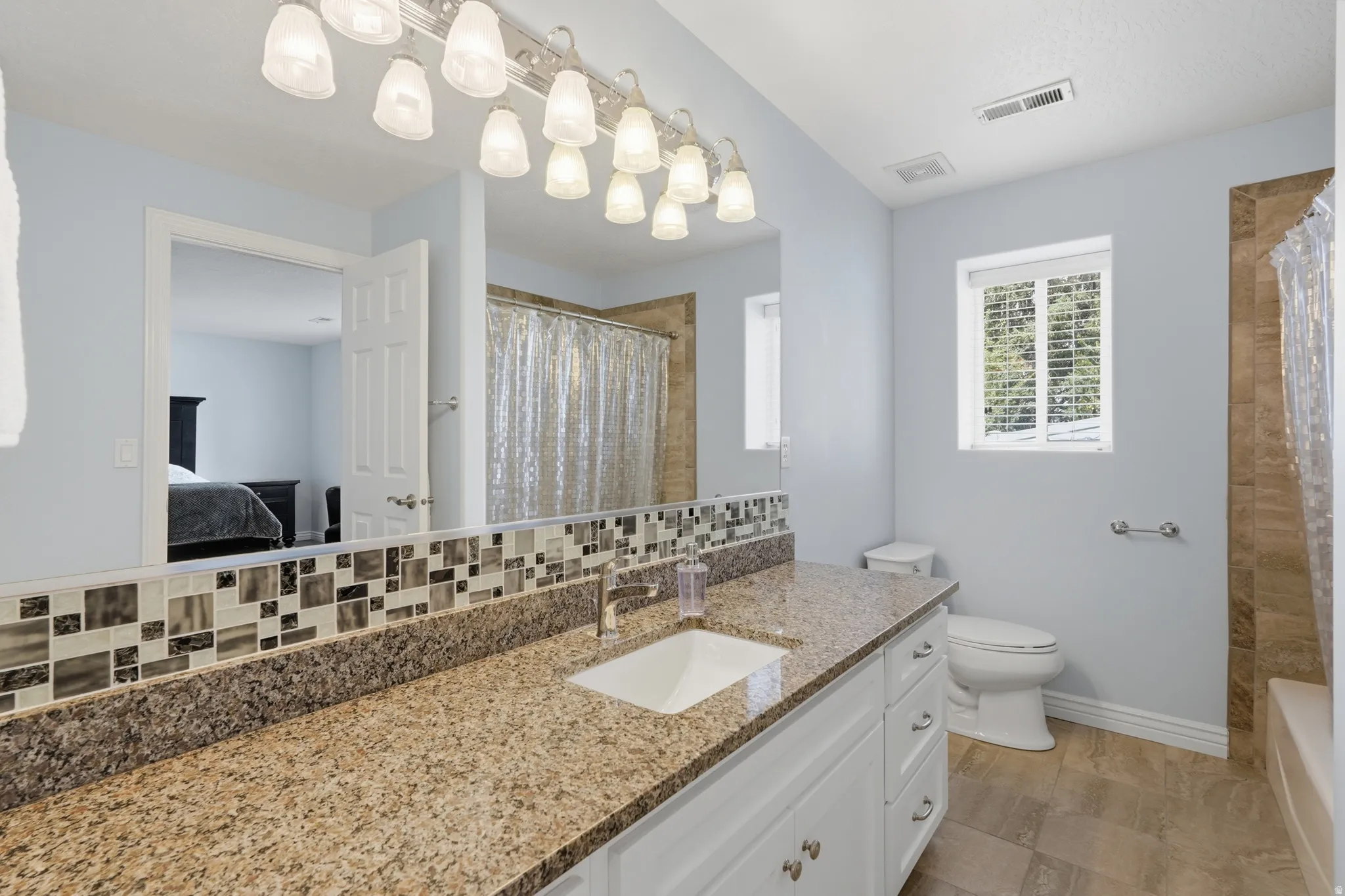 Vanity with a granite-finish countertop, undermount sink, and polished chrome faucet