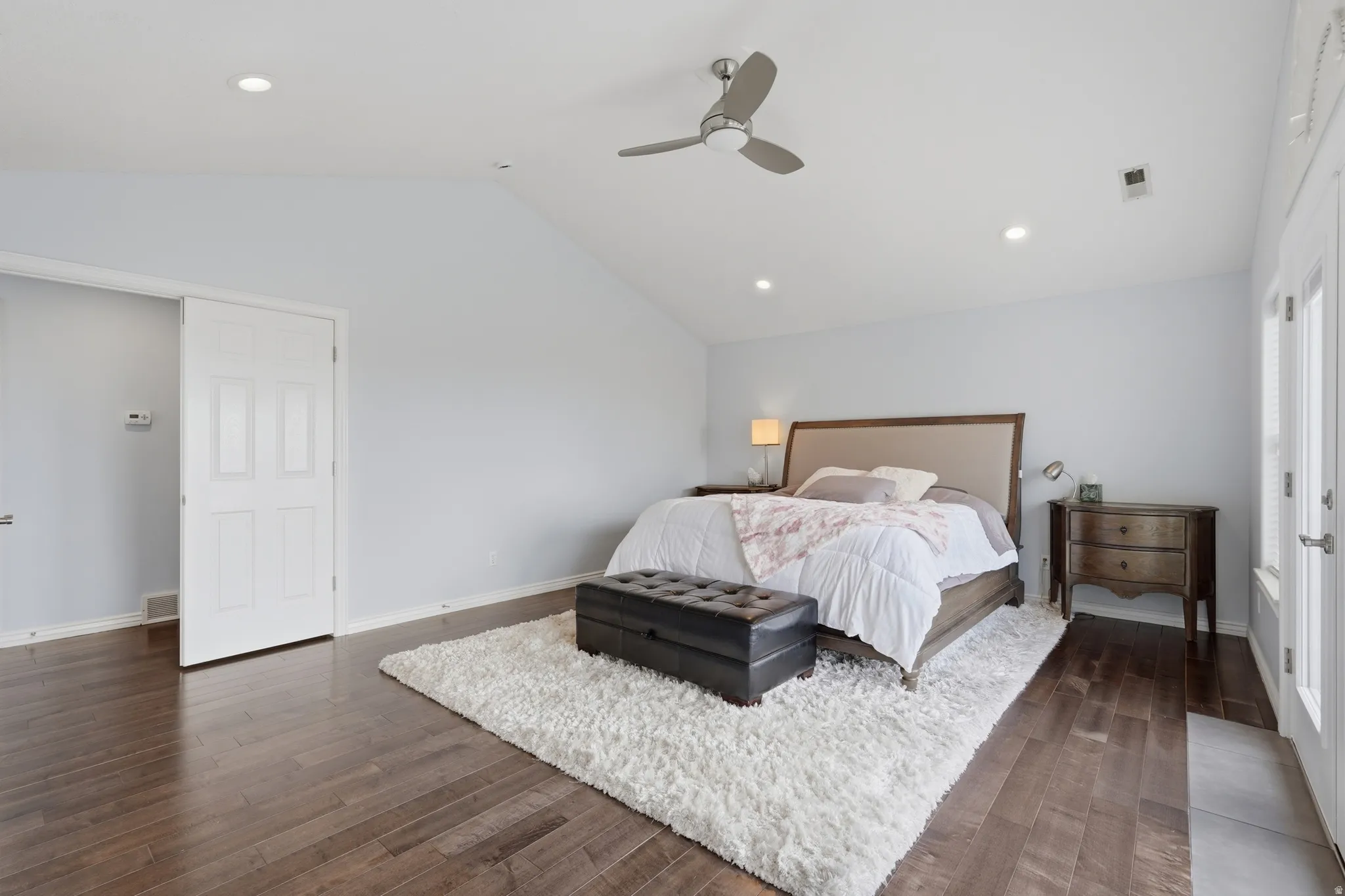 Vaulted ceiling with a ceiling fan, recessed lighting, wood-finish flooring, and white paneled doors