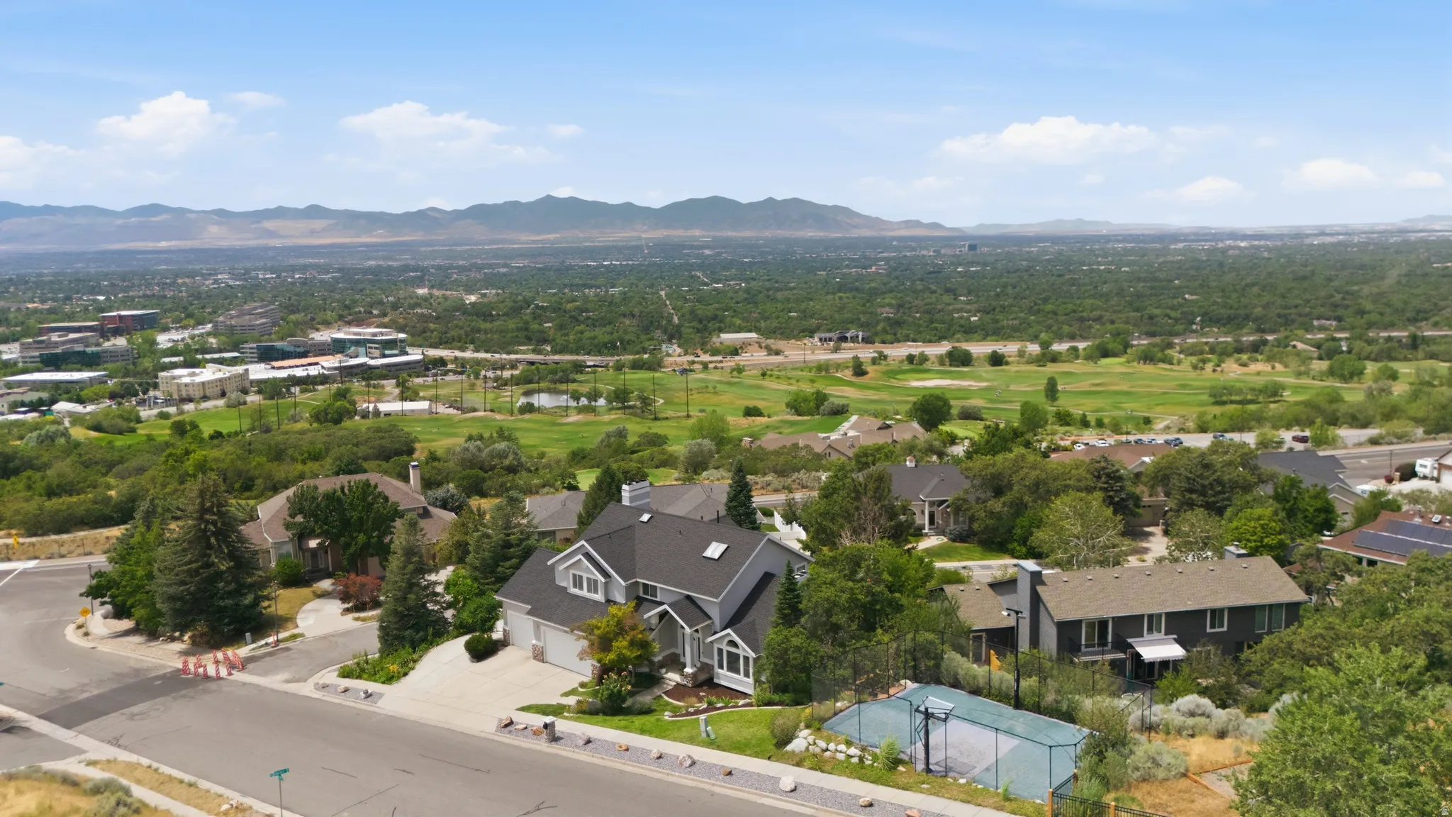 Expansive residential area with mountain backdrop, surrounded by dense greenery and a golf course