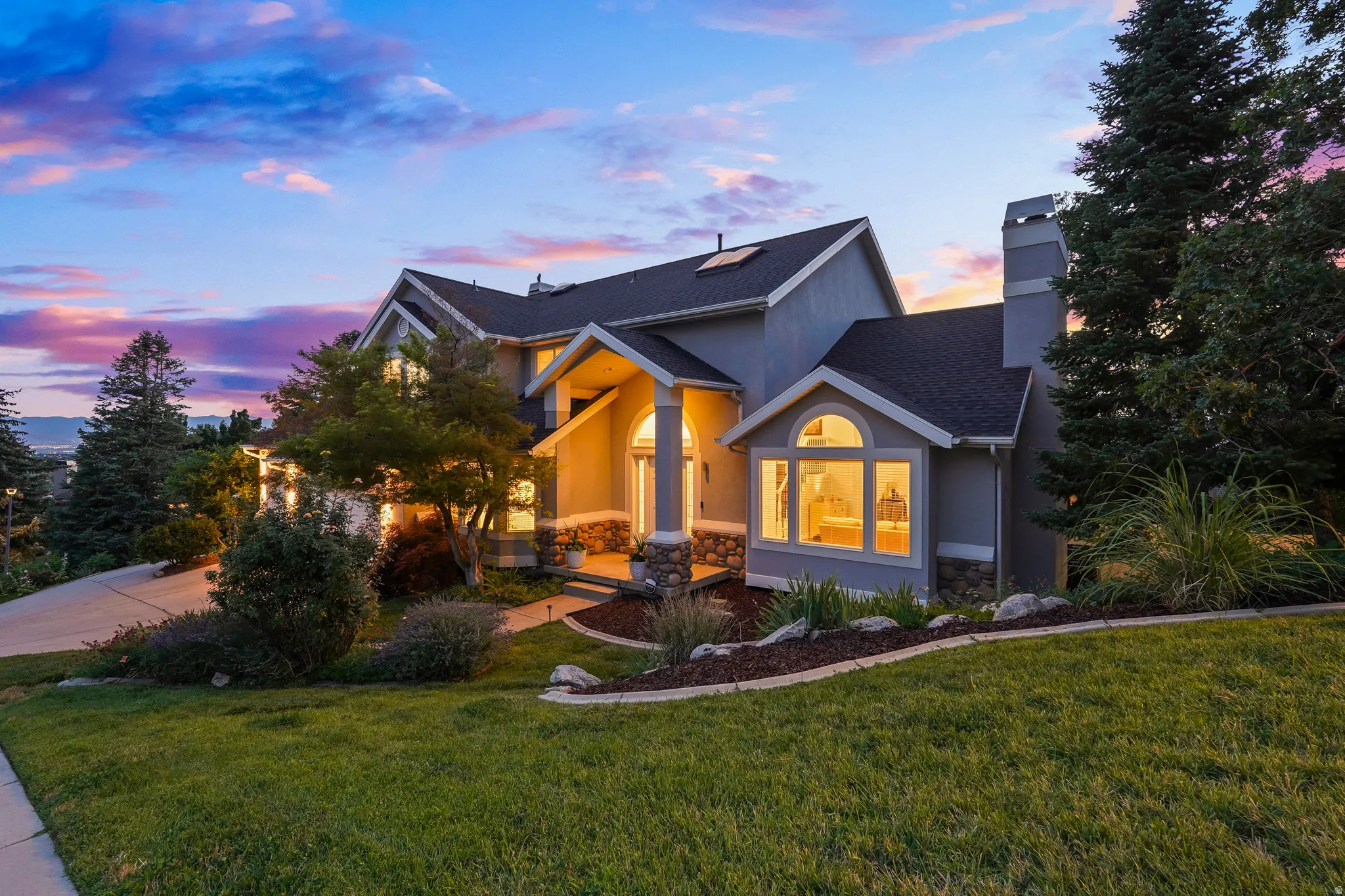 Two-story stucco exterior with stone accents, arched entryway, bay window, and a dark shingle roof