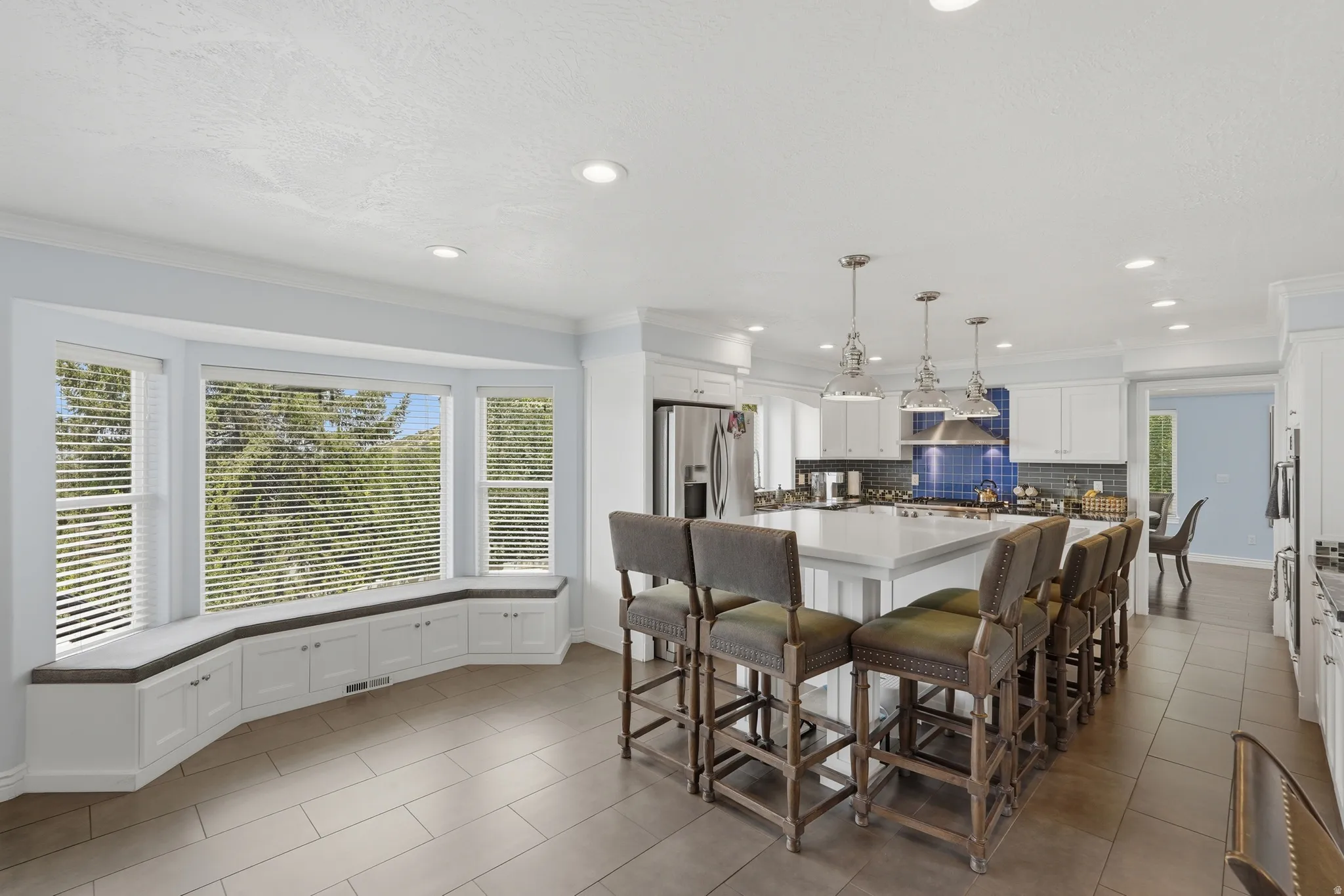 Kitchen with recessed lighting, white cabinetry, a central island with counter seating, stainless steel appliances, and a tiled backsplash