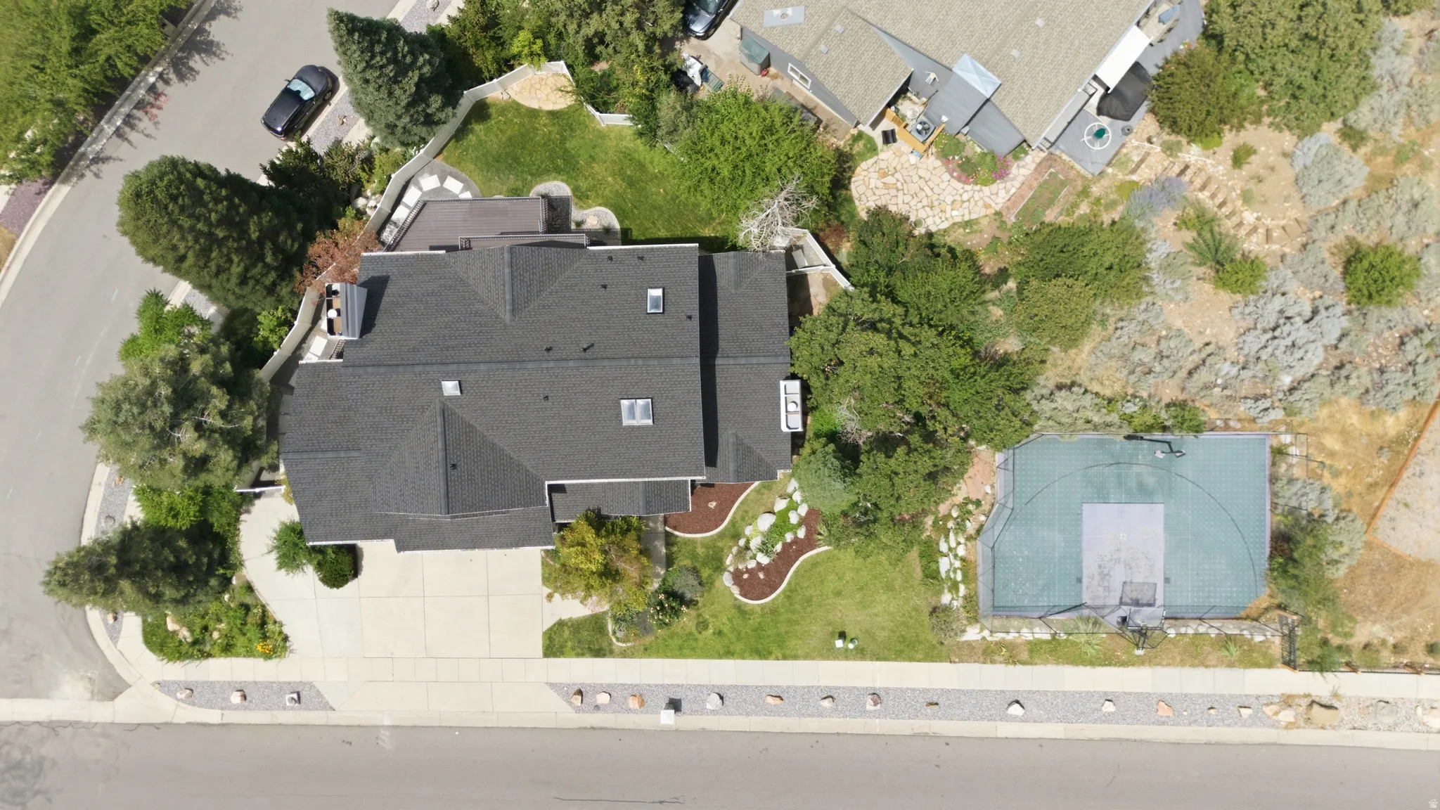 Expansive paved driveway, attached multi-level deck, well-maintained landscaping, and integrated basketball court