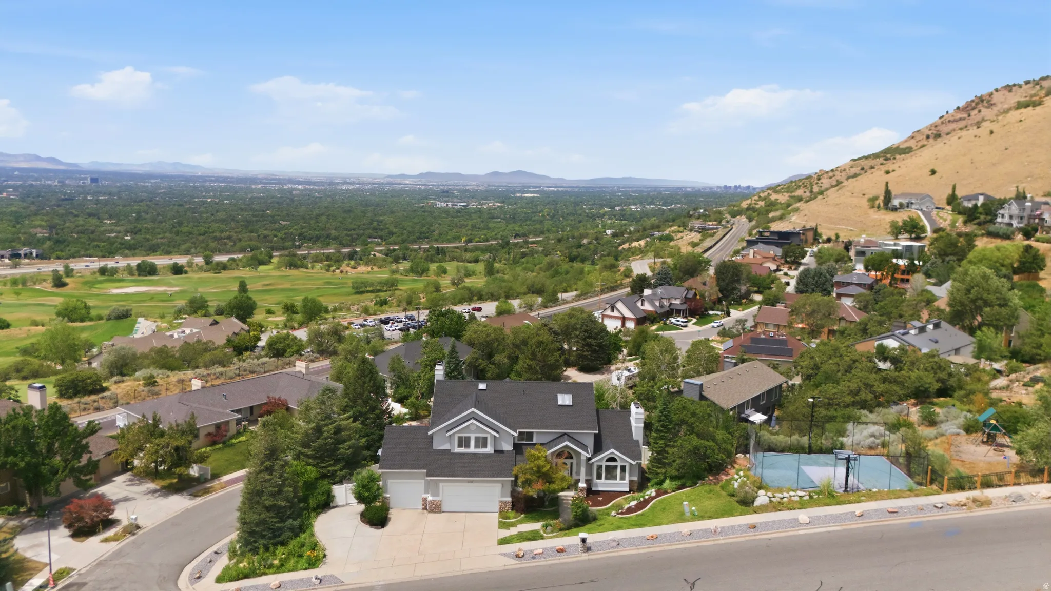 Two-story residence with a two-car garage, mature landscaping, and an adjacent sports court