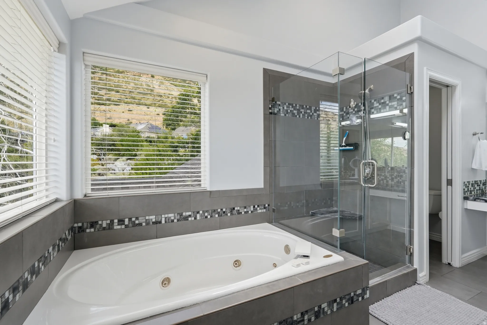 Spa-style jetted tub with tile surround and mosaic accent