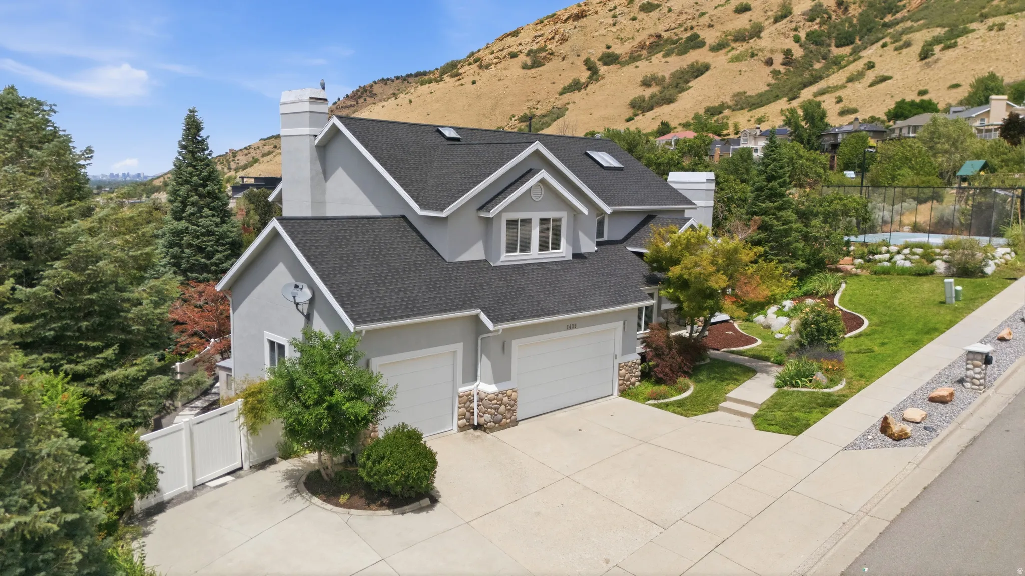 Stucco exterior with stone accents, two-car garage, concrete driveway, front walkway, and mature landscaping