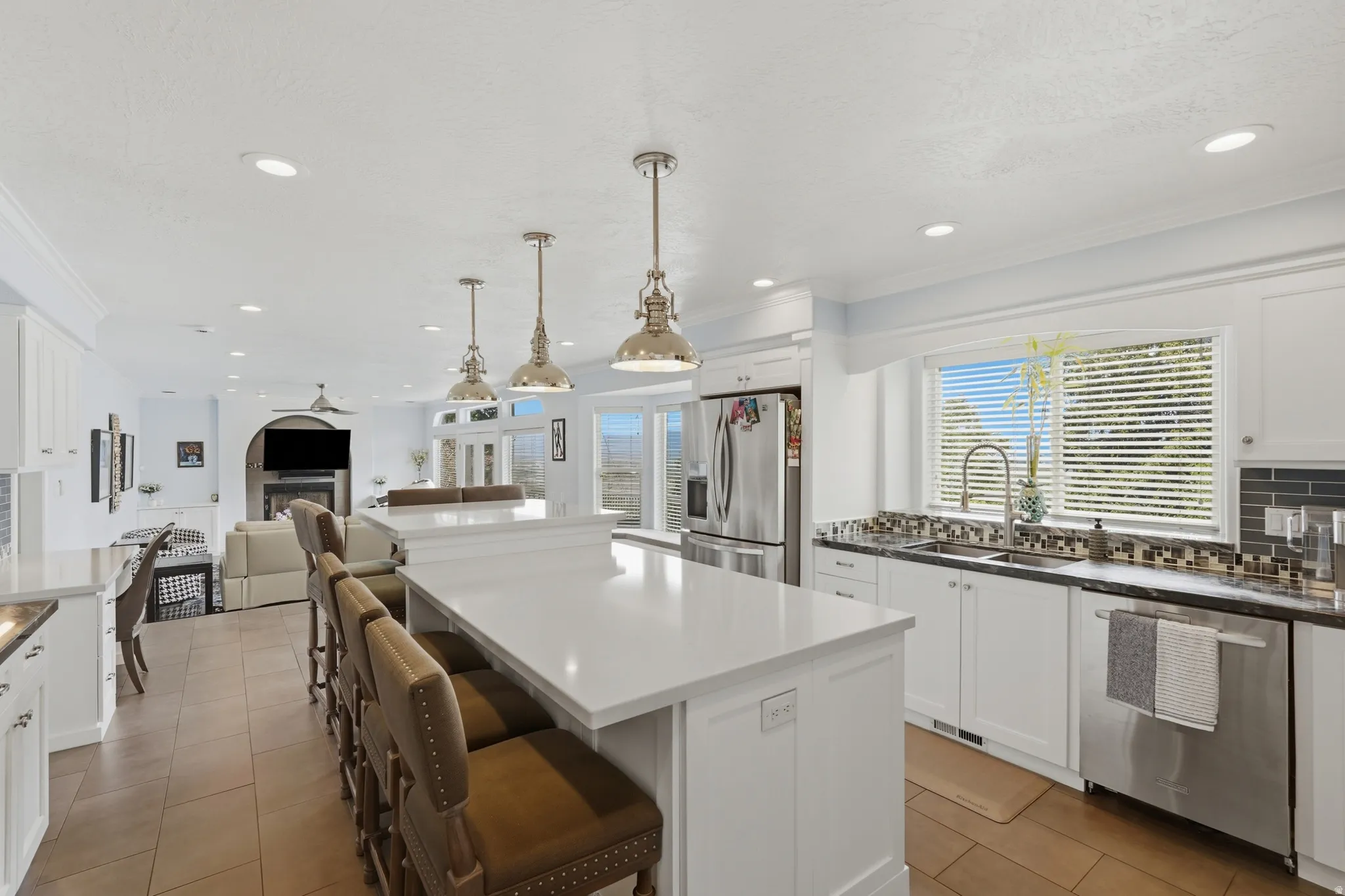 Expansive kitchen island with a light-toned countertop, stainless steel appliances, white cabinetry, and recessed lighting