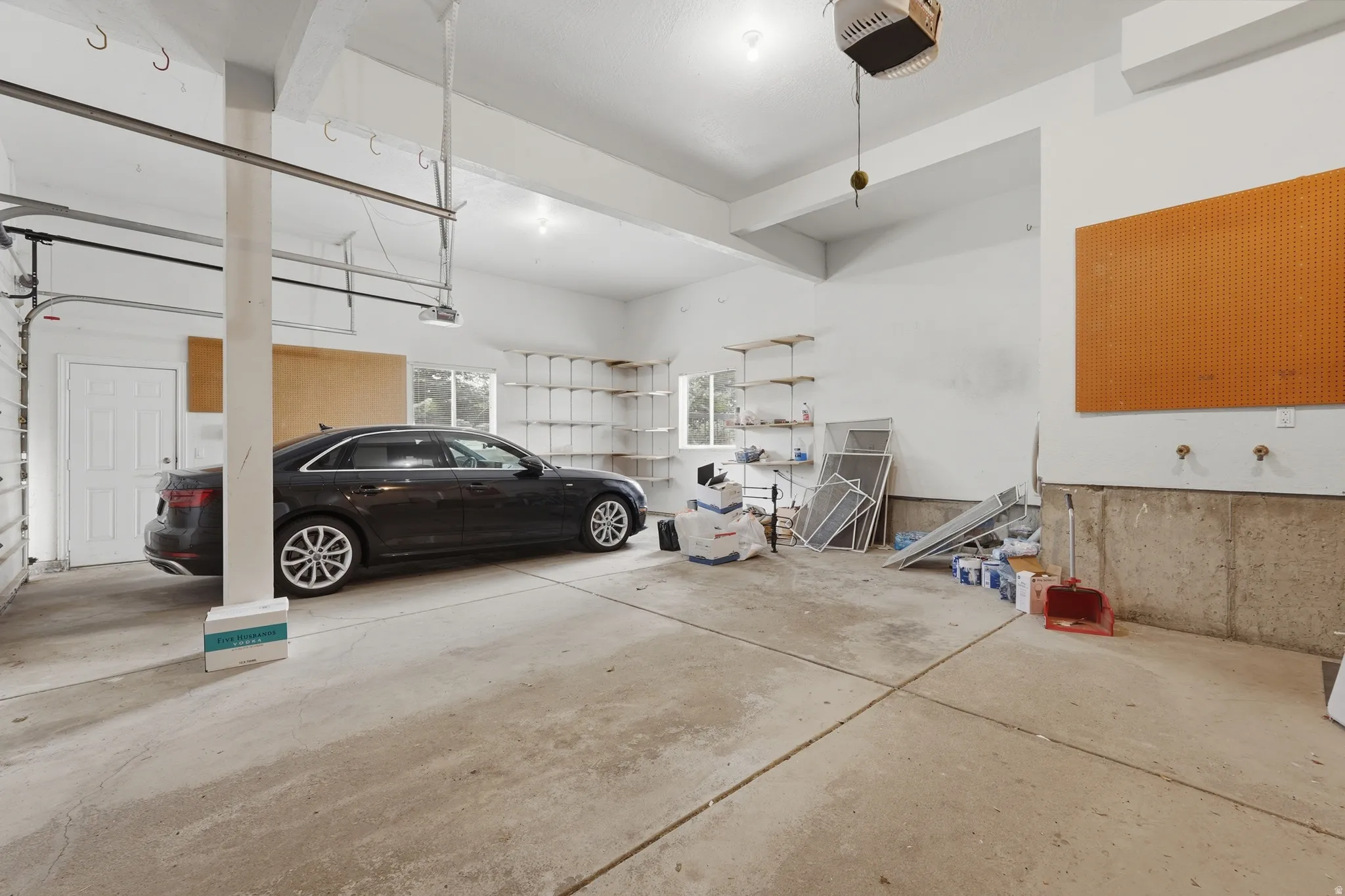 Expansive garage space with concrete flooring, overhead lighting, and built-in wall shelving