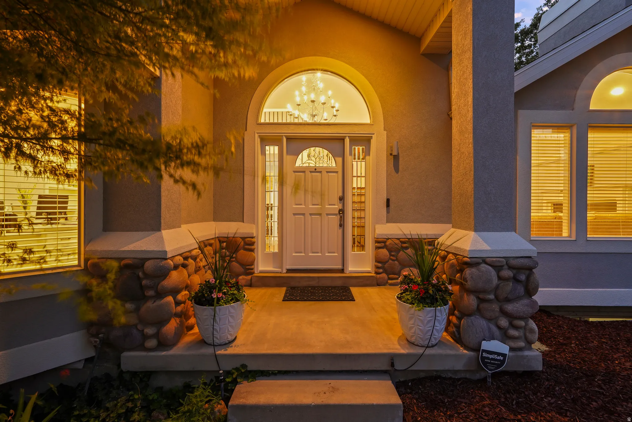 Arched entry door with decorative glass, flanked by stone-clad columns and an arched transom window above
