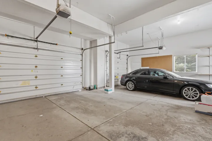 Spacious garage with multiple overhead doors, concrete flooring, and built-in shelving