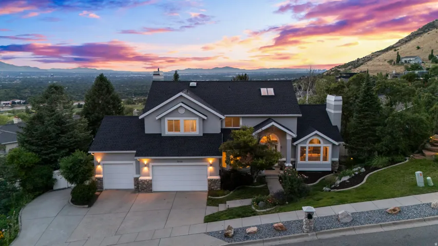 Two-story residence with a gray exterior, dark shingle roof, attached two-car garage, and stone accents