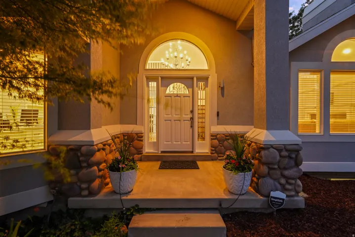 Arched entry door with decorative glass, flanked by stone-clad columns and an arched transom window above