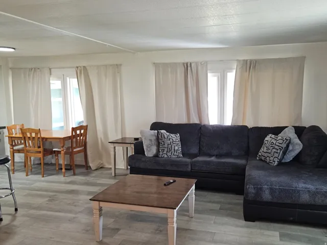 Open concept living area with wood-finish flooring, white walls, and multiple windows