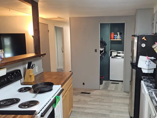 White kitchen appliances, wood-finish countertops, stainless steel sink, wood-finish flooring, and light gray cabinetry
