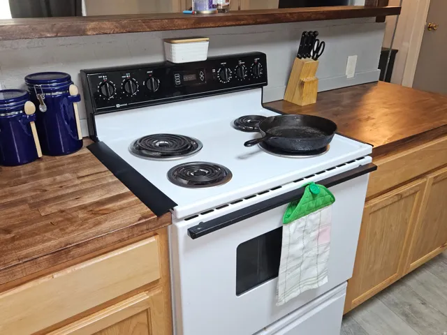 White electric range with a built-in oven, complemented by natural wood cabinetry and wood-finish countertops