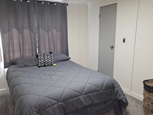 White paneled walls, gray door with metal hardware, and gray window treatments
